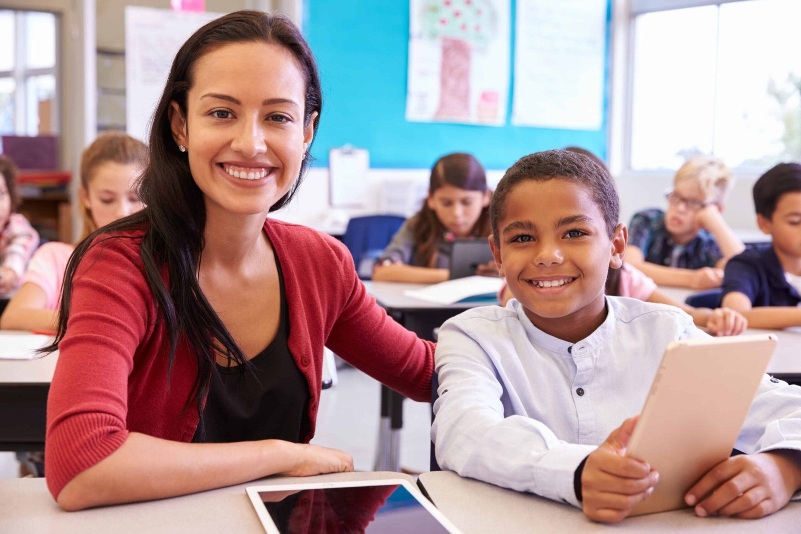 Portrait of teacher with elementary school boy at his desk EDUCATION / TEACHER ASSISTANTS INTERVIEW QUESTIONS AND ANSWERS