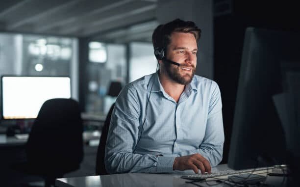 Shot of a young call centre agent working on a computer in an office at night